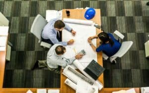 three people sitting beside table communicating IT's Business Value