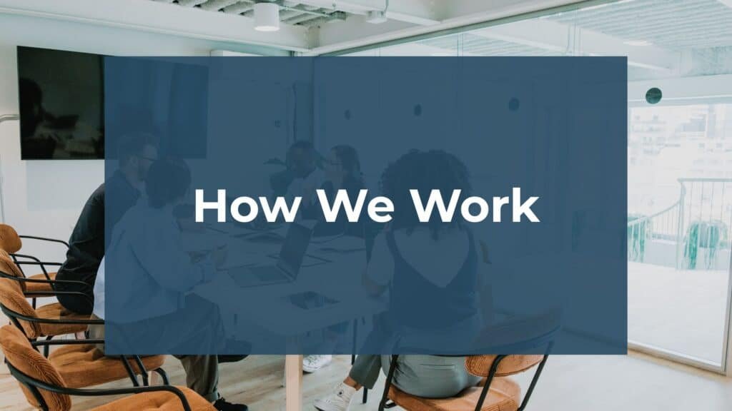 A group of people sits around a table in a modern office meeting room. A large blue rectangle with the words “How We Work” in bold white text covers the center of the image.